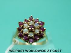 A 9ct gold ring set with opals and rubies in a cluster (size O)