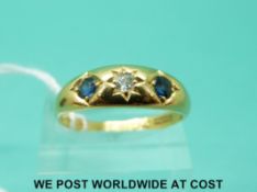 An 18ct gold ring set with a diamond and two sapphires (size V)