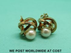 A pair of 9ct gold earrings in a knot design set with a pearl