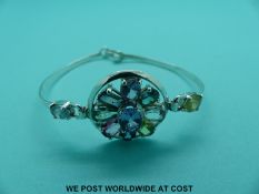 A silver bracelet set with multi-coloured sapphires in a circle including round cut, emerald cut,