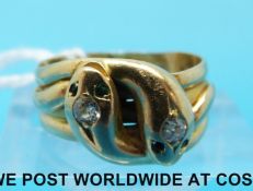An 18ct gold ring in the form of two snakes each set with an old cut diamond and with emerald and
