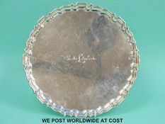 A hallmarked silver salver with shaped edge, raised on four paw feet,