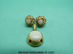 A 14ct gold pendant set with an opal cabochon and a pair of 9ct gold earrings set with opals