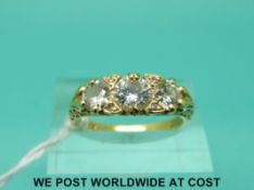 An 18ct gold ring set with three diamonds in a scrolling setting, the centre diamond measuring 0.