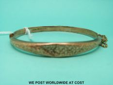 A 9ct gold bangle with foliate decoration (6.