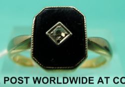 An 18ct gold ring set with onyx with a diamond to the centre in a platinum setting (Size P)
