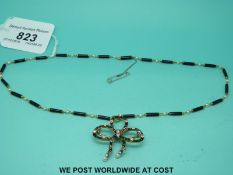 A Victorian gold brooch/pendant in the form of a bow set with black enamel,