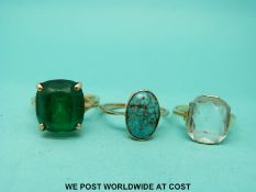 A yellow metal ring marked 583 set with a green stone and two yellow metal rings one set with a