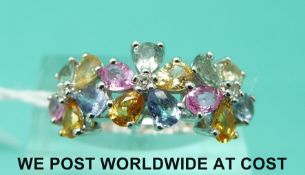 A 9ct white gold ring set with multi coloured sapphires in three flower clusters (size M)