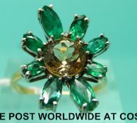 An 18ct gold ring set with emeralds and a topaz in a large floral design (size O)