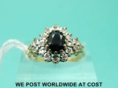 A 9ct gold ring set with a sapphire surrounded by diamonds (size L/M)