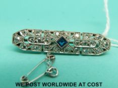 A white metal brooch set with a sapphire and diamonds