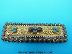 An unusual buckle set with an enamel border and turquoise and garnet cabochons