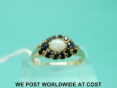 A 9ct gold ring set with an opal surrounded by sapphires (size N)