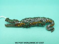 A silver brooch in the form of a crocodile set with green and yellow paste