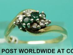 A 9ct gold ring set with three emeralds and six diamonds in a twist setting (size P)