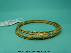 Four Middle Eastern yellow metal bangles with ridged and cross decoration (29.