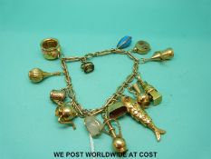 A 9ct gold bracelet with fourteen yellow metal and 9ct gold charms including a fish, clock,