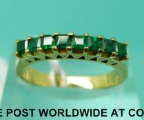 A yellow metal ring marked 18ct set with eight square emeralds (size O)