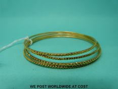 Four Middle Eastern yellow metal bangles with zig zag decoration (27g)