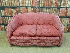 A 19th/20thC two seater burgundy upholstered sofa on oak bun feet and metal castors