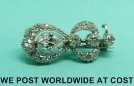 A platinum brooch set with a central pear cut diamond surrounded by a ring of smaller diamonds in