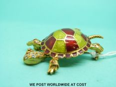 A yellow metal brooch in the form of a tortoise set with green and red enamel to the body and