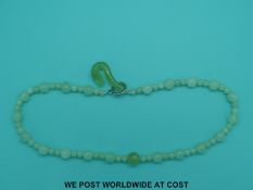 A jadeite or serpentine necklace with 65 spherical beads some carved in a spirlling pattern and