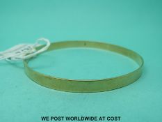 A yellow metal bangle marked 9ct gold (12.