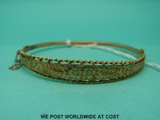 A 9ct gold bangle with engraved foliate decoration (5.