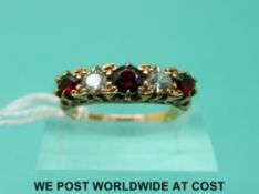 A 9ct gold ring set with alternate garnet and clear stones (size K/L)