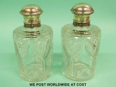 A pair of Fabergé silver topped cut glass scent bottles with ribbon decoration,
