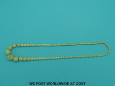 An ivory necklace of over 100 graduated spherical beads, some with carved decoration, 50cm long.