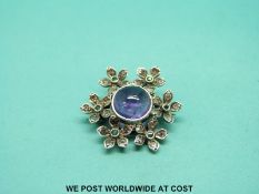 A suffragette brooch set with an amethyst cabochon surrounded by diamonds and emeralds in the form