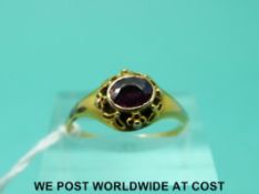 A Victorian yellow metal ring set with an amethyst in a pierced setting (size N)