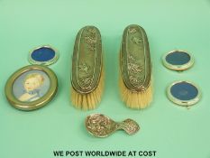 A pair of hallmarked silver-backed brushes and three small circular photo frames,