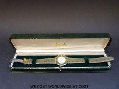 Harrods Delma gold plated wristwatch with mother of pearl face and green bezel with Roman numerals,