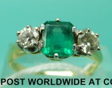 An 18ct gold ring set with an emerald cut emerald of approximately 1ct and a diamond to each side
