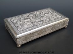A possibly white metal cigarette box with embossed decoration depicting mythical creatures,