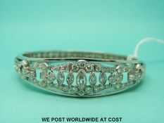 A white metal bangle set with a marquise cut diamonds surrounded by round cut diamonds in a buckle