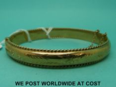 A 9ct gold bangle with engraved decoration (14.