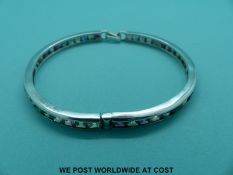 A silver bangle set with a multi-coloured princess cut sapphires