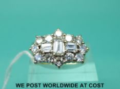 An 18ct gold ring set with twelve round brilliant cut diamonds and three rectangular trap cut