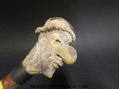 A carved deer horn walking cane with a caricature knop,