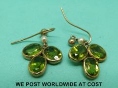 A pair of 9ct gold earrings set with peridots and a pearl to each