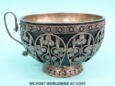 An Eastern white metal cup with filigree cage exterior, turned wooden bowl and white metal liner,
