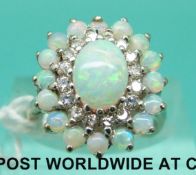 An 18ct white gold ring set with an oval opal cabochon surrounded by a circle of diamonds then a