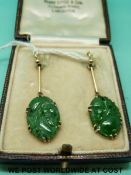 A pair of yellow metal earrings set with carved jade panels,