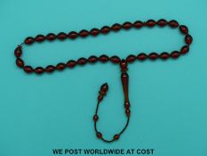 A set of amber prayer beads with 38 translucent beads on plaited string, length of drop 35cm.