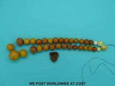 An amber necklace of 29 graduated beads, the largest 28mm in diameter and four ivory beads,